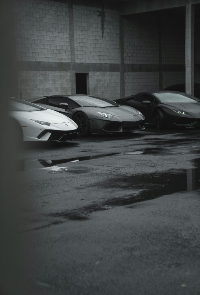 pexels-photo-11963311-11963311 A trio of sleek sports cars parked in an industrial lot. Perfect for luxury automotive themes.
